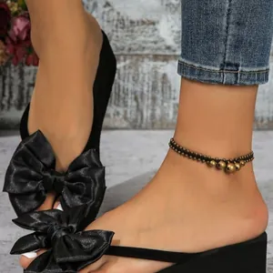 Elegantes chanclas de plataforma negras con gran lazo de satén y tobillera vintage.