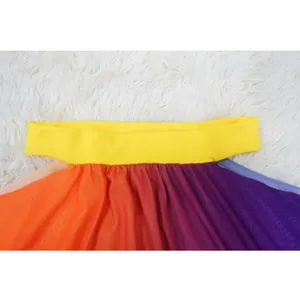 Close-up detail of yellow waistband and vibrant rainbow mesh fabric of a beach skirt.