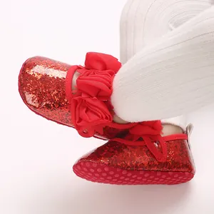 Nahaufnahme von roten Glitzer-Babyschuhen mit großer Stoffblume und rutschfester weicher Sohle.