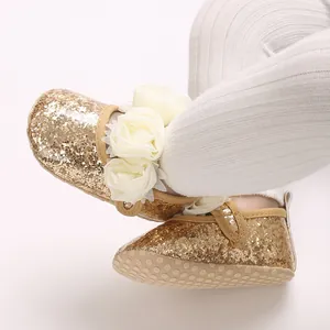 Nahaufnahme von goldenen Glitzer-Babyschuhen mit Chiffonblumen und weicher, rutschfester Sohle