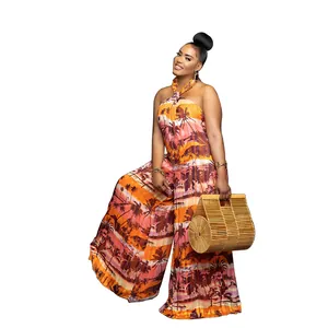 Full view of a tropical palm print halter neck backless wide-leg jumpsuit with bamboo bag.