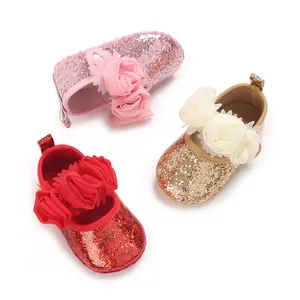 A detailed view showing three colors of sequined baby shoes with large chiffon flowers