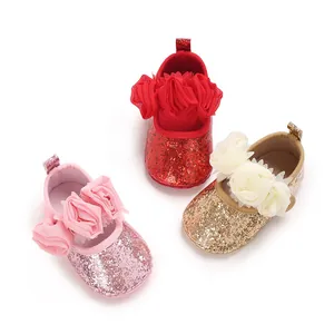Close-up of glitter baby walker shoes with decorative mesh flowers in pink, red, and gold