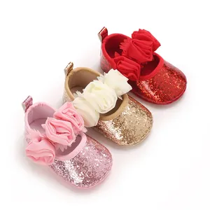 Close-up of glitter baby walker shoes in pink, gold, and red with floral accents