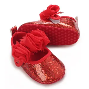 Nahaufnahme von roten Pailletten-Babyschuhen mit lebhaften Stoffblumen-Details