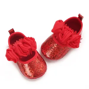 Makro-Detailansicht der roten glitzernden Baby-Lauflernschuhe mit großen Stoffblumen-Akzenten