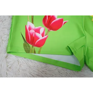 Close-up detail of bright green floral shorts featuring pink tulip print and quality hem stitching