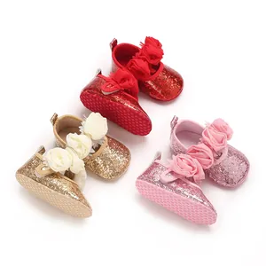Glittery baby walker shoes in red, gold, and pink with decorative fabric flowers.