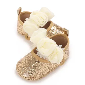 Nahaufnahme goldener Baby-Glitzerschuhe mit eleganten weißen Chiffon-Blumendetails