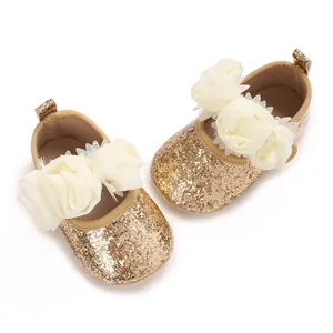Nahaufnahme der goldenen Glitzer-Babyschuhe mit zarten weißen Stoffblumen-Verzierung