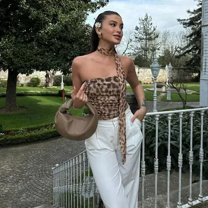 Modelo de moda con top palabra de honor de leopardo y bufanda a juego en un jardín.