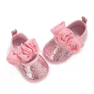 Nahaufnahme von funkelnden rosa Babyschuhen mit eleganten Akzenten aus Chiffonblumen