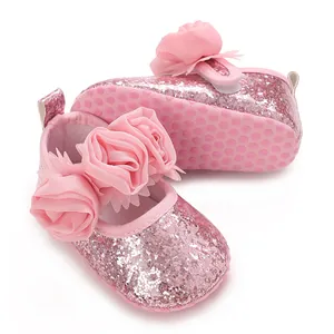 Detailansicht der Blumenverzierung und des glitzernden Stoffes der rosa Babyschuhe.