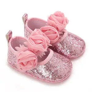 Nahaufnahme von rosa glitzernden Babyschuhen mit drei dekorativen Mesh-Stoffrosen
