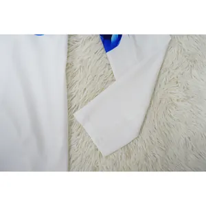 Detailed shot of white suit sleeve cuff with blue floral print on white fur background