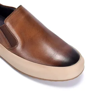 Detailopname van premium bruine leren loafers met gepolijste neus en beige rubberen zool.