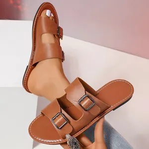Detail von braunen Retro-Flach-Sandaletten mit verstellbaren Doppelschnallen und Ziernähten