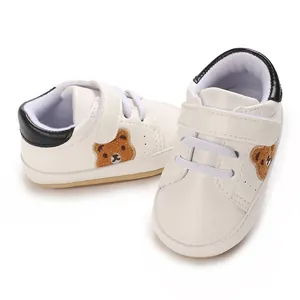 Close-up van witte babysneakers met schattig berenborduurwerk en zachte zool