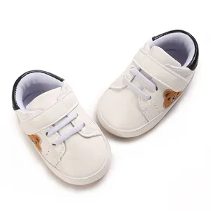 Detail van witte babyschoenen met berenborduursel en handige klittenbandsluiting