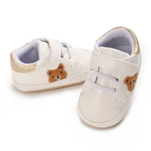 Witte babysneakers met schattige berenborduursels en gouden details van dichtbij