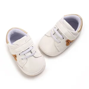 Gedetailleerd bovenaanzicht van witte babysneakers met schattige geborduurde beer.