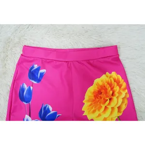 Close-up detail of vibrant pink shorts with blue tulips and yellow dahlia floral print