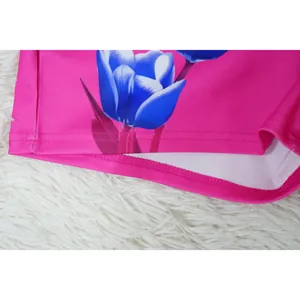 Close-up of stitching and blue tulip print on the hem of high-waisted pink suit shorts