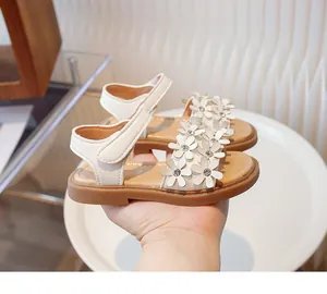 Detailed view of white girls' sandals with 3D flower decorations and soft brown soles