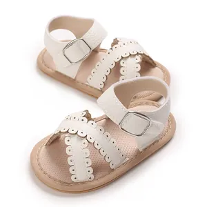 Detail of baby girl white sandals featuring scalloped edges and adjustable buckle strap.