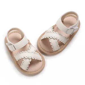 Elegant white baby girl sandals with decorative scalloped cross straps and buckle