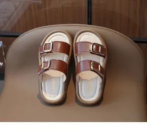 Nahaufnahme von stilvollen braunen Mädchen-Sandalen mit Doppelriemen und Goldschnallen