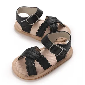 Close-up detail of black scalloped leather straps on infant girl sandals with soft tan sole