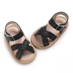 Top view of black criss-cross toddler sandals featuring scalloped edges and buckles