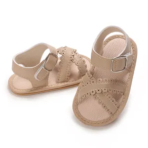 Detailed view of stylish beige baby girl sandals with scalloped straps and buckle.