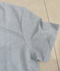 Vue détaillée montrant la texture en maille gaufrée d'un polo gris pour hommes