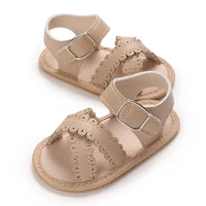 Close-up of beige baby girl sandals featuring scalloped cross-straps and buckle