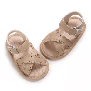 Close-up of baby girl sandals with scalloped edges and buckle strap in beige leather.