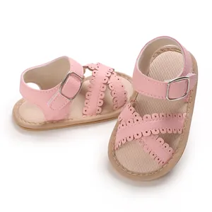 Close-up of stylish pink baby girl sandals with scalloped edges and metal buckle straps