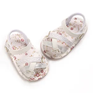 Close-up van witte baby sandalen met bloemenprint, kant en vlinder accenten voor baby.