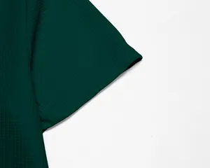 Gros plan de la texture du tissu gaufré vert foncé sur un polo à manches courtes pour homme.