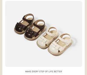 Close-up detail of elegant toddler girls' sandals in brown and cream synthetic leather.