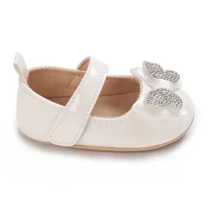 Detalle de zapatos de princesa en PU blanco para bebé con lazo de pedrería.