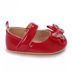 Detalle de zapatos de princesa para bebé rojos con un diseño de lazo de strass brillante