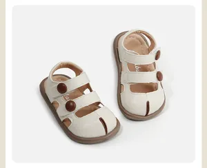 Sandalias beige para niños pequeños con cierre de velcro y botones marrones.