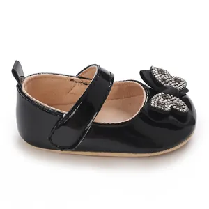 Primer plano de un zapato de charol negro para bebé niña con un lazo de pedrería