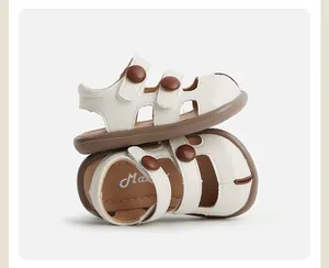 Detalle de sandalias crema para niños con botones marrones y diseño de punta cerrada