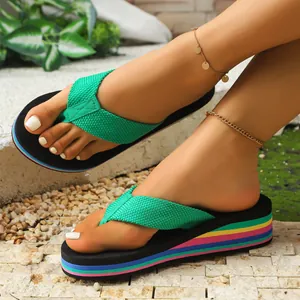 Primo piano di infradito da donna con zeppa arcobaleno e cinturini intrecciati verdi.