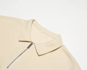 Détail montrant la texture gaufrée et la fermeture éclair d'un polo beige pour homme de qualité.