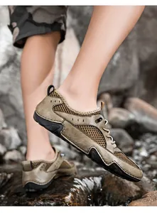 Detailweergave van de kaki lederen en mesh outdoor herensneakers op rotsen