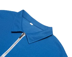 Vue détaillée du tissu en maille gaufrée bleue et du zip argenté sur un polo pour hommes
